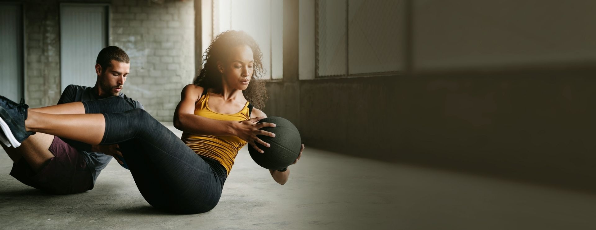 Two Gold’s Gym members doing medicine ball core training during a functional workout
